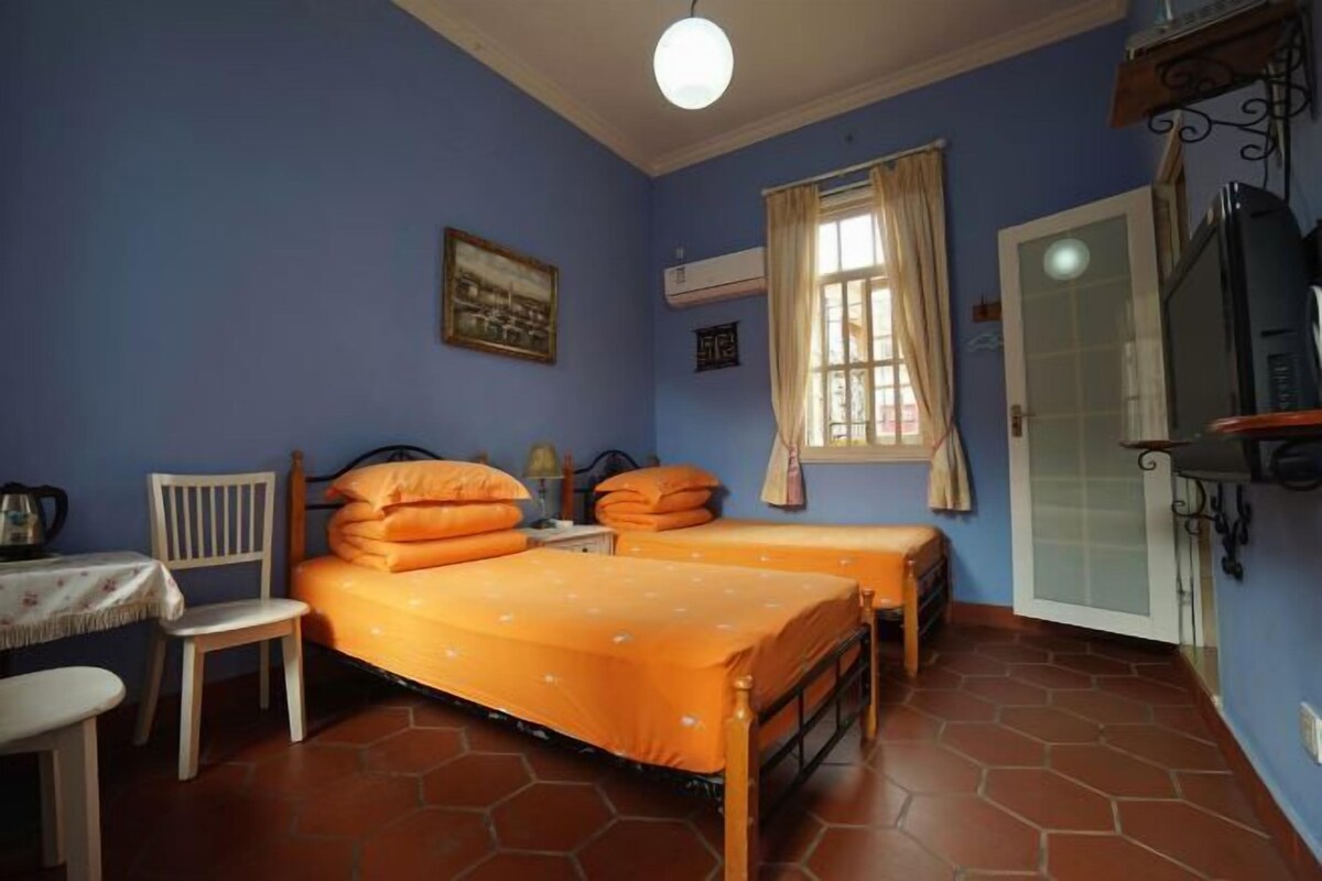 Una habitación con dos camas, una silla, una mesa y un televisor.