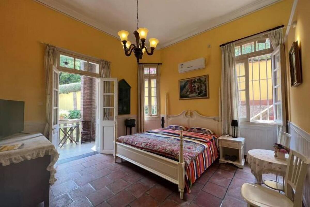 A bedroom with a bed, a chair, a table, and a chandelier.
