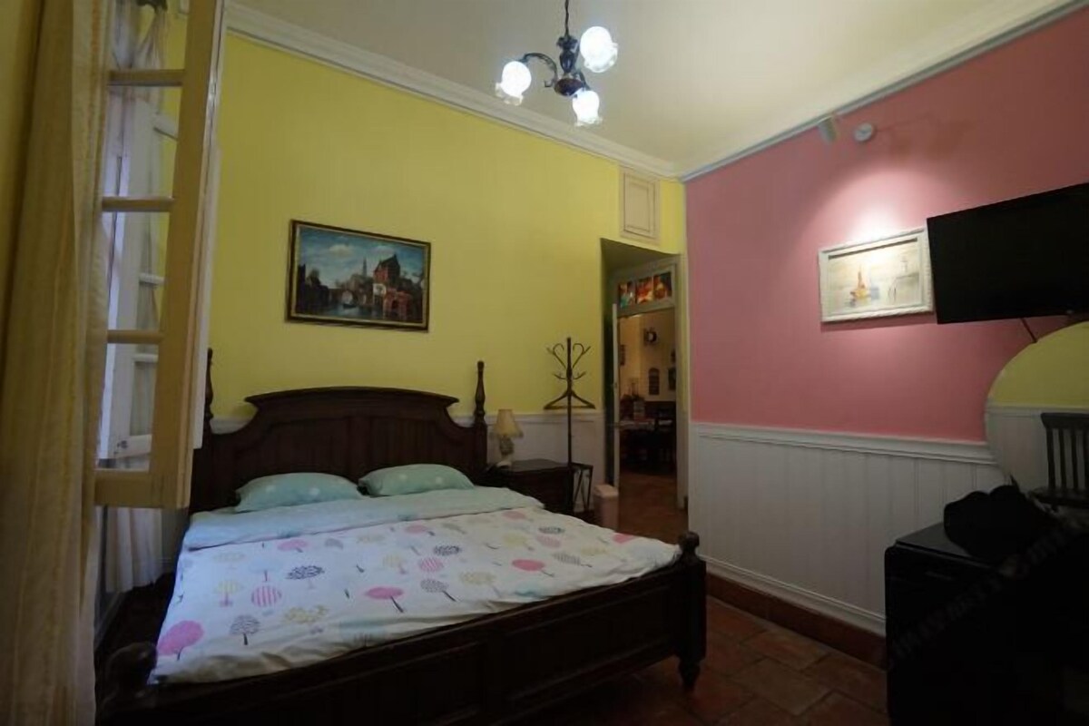 Un dormitorio con una cama de madera, un cuadro en la pared y un televisor montado.