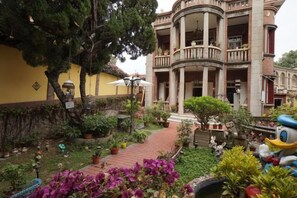 A courtyard with a building featuring a balcony, potted plants, and a pathway. - Chuanwu Old Villa Family Hotel (Xiamen)
