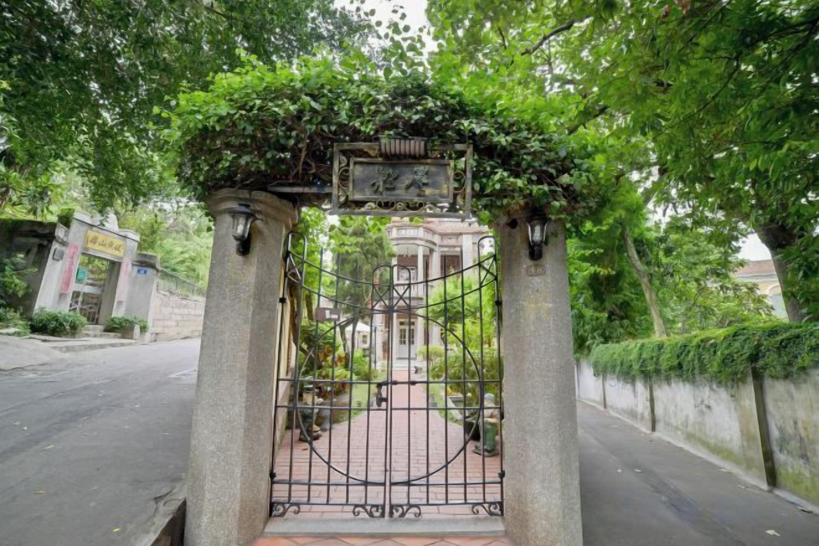 A gated entrance with a wrought iron gate, a stone archway, and a plaque.