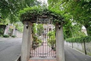 Una entrada protegida con una reja de hierro forjado, un arco de piedra y una placa.