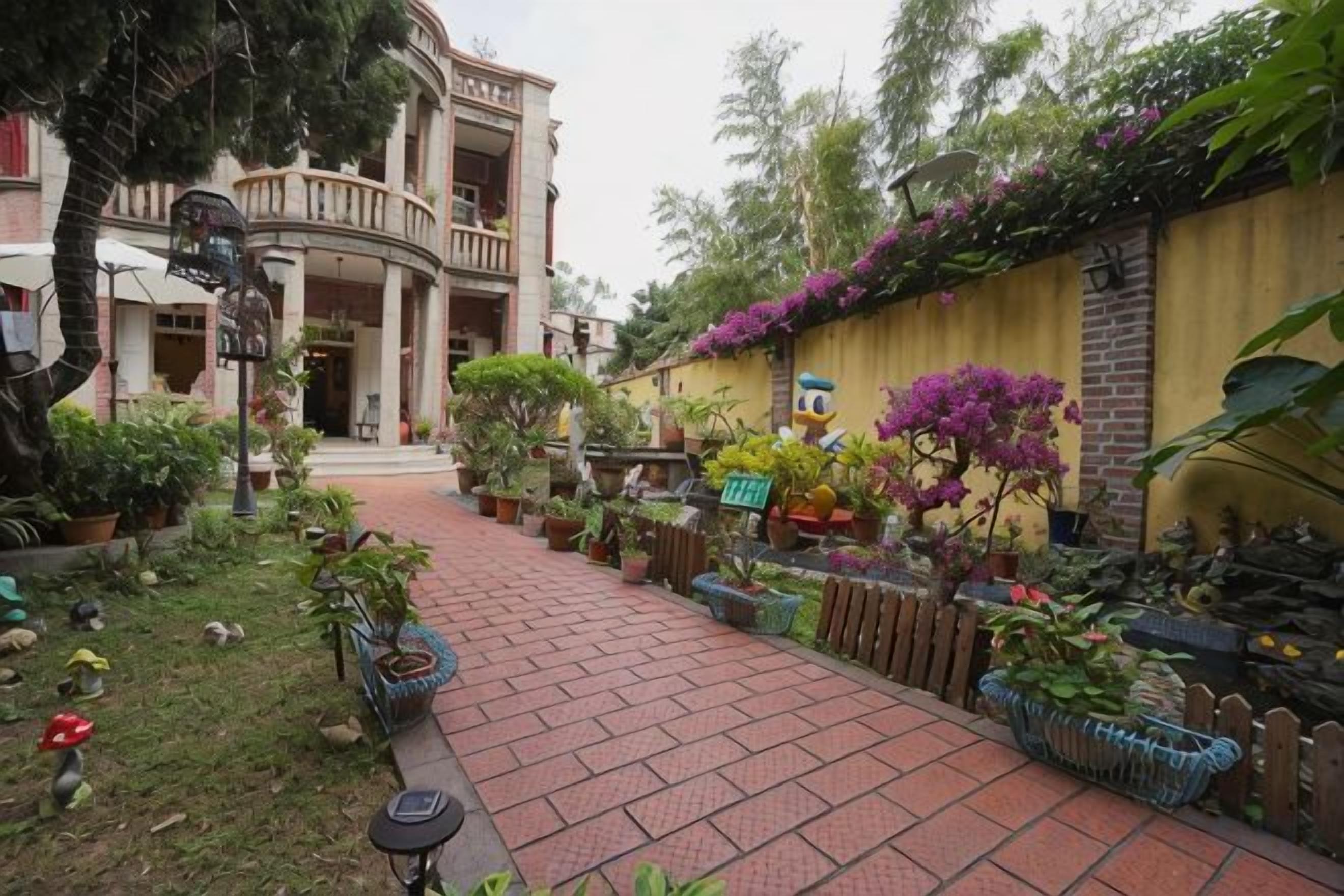 A garden pathway leading to a building with a balcony, surrounded by various potted plants and flowers.
