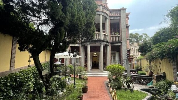 A building with a central courtyard, surrounded by potted plants and a brick pathway. - Chuanwu Old Villa Family Hotel (Xiamen)