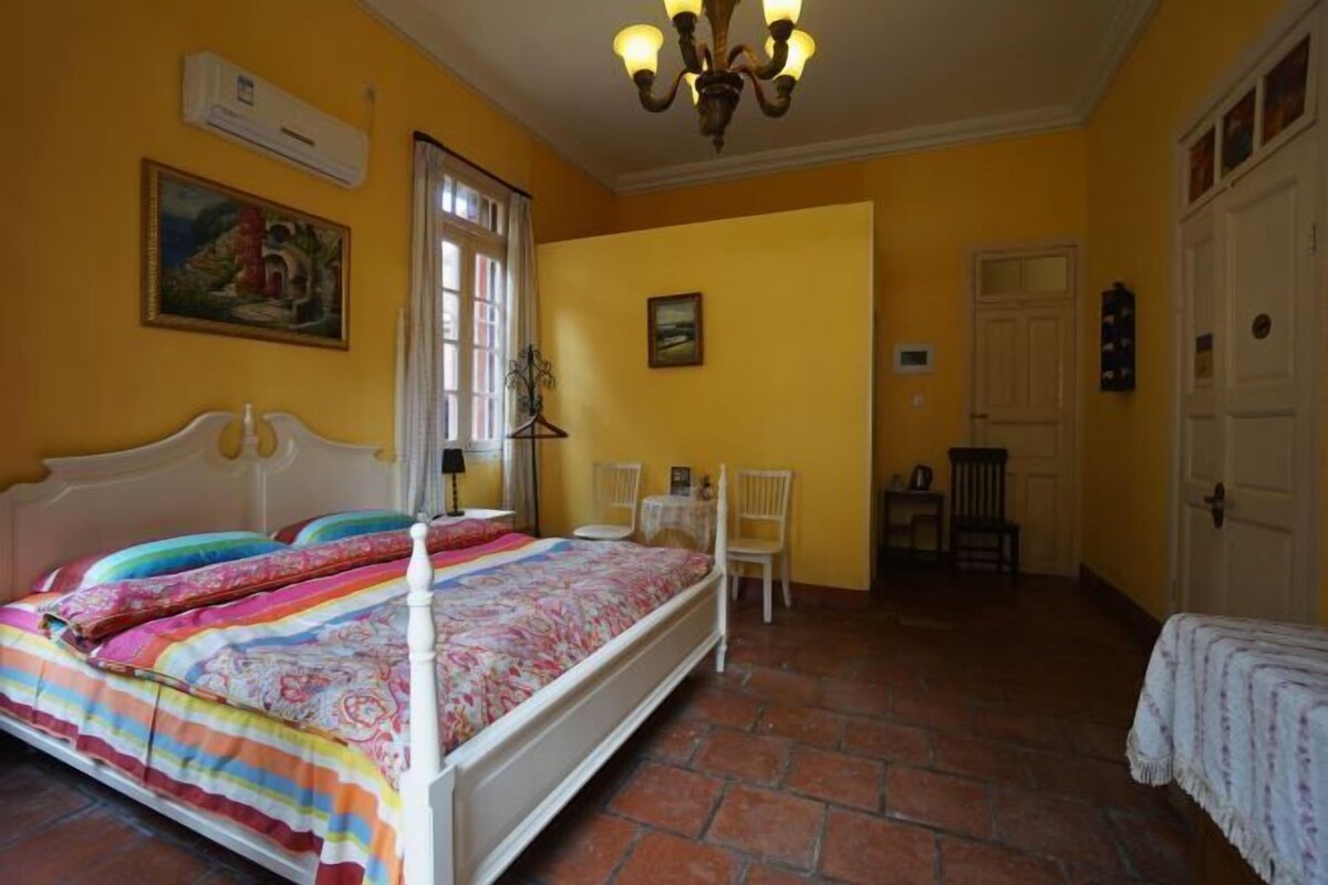 Un dormitorio con cama, una silla, una mesa y una puerta.