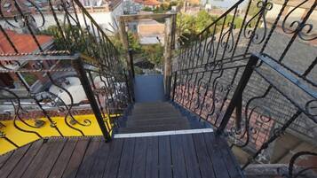 A wooden staircase with black railings leading to a building entrance.