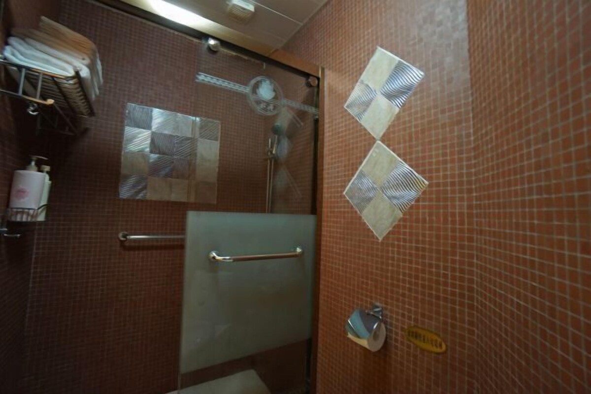 Un baño con cabina de ducha de vidrio, un perchero y un dispensador de jabón.