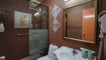 A bathroom with a glass shower enclosure, a white toilet, a sink with a mirror, and a telephone.
