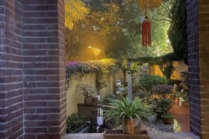 A brick-walled corridor with hanging plants and a pathway leading to a door. - Chuanwu Old Villa Family Hotel (Xiamen)