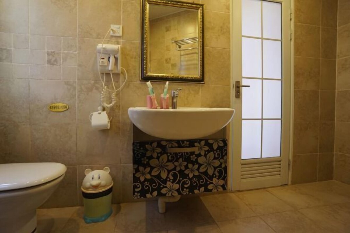 Un baño con inodoro, lavabo, espejo y cubo de basura.