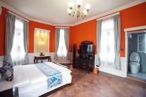 Un dormitorio con cama, cómoda, televisor y baño.
