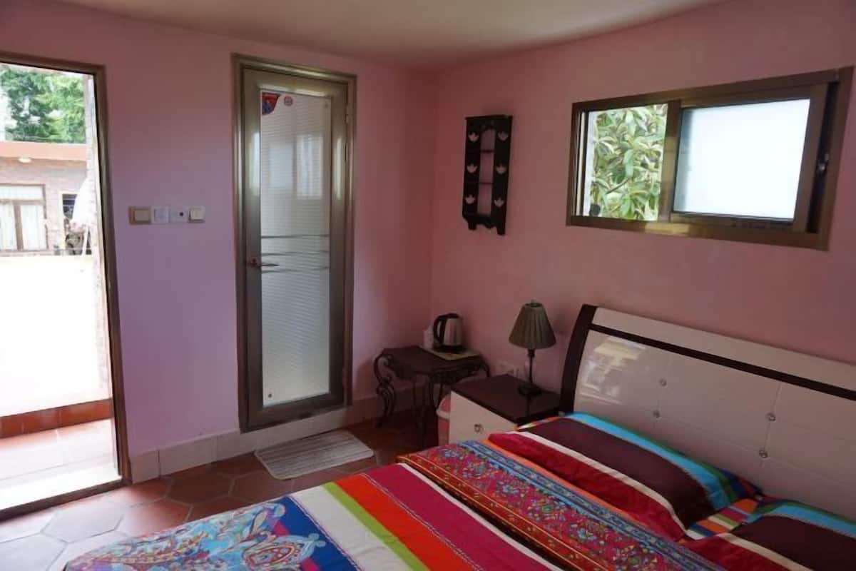 A bedroom with a bed, a desk, a chair, a window, and a door.