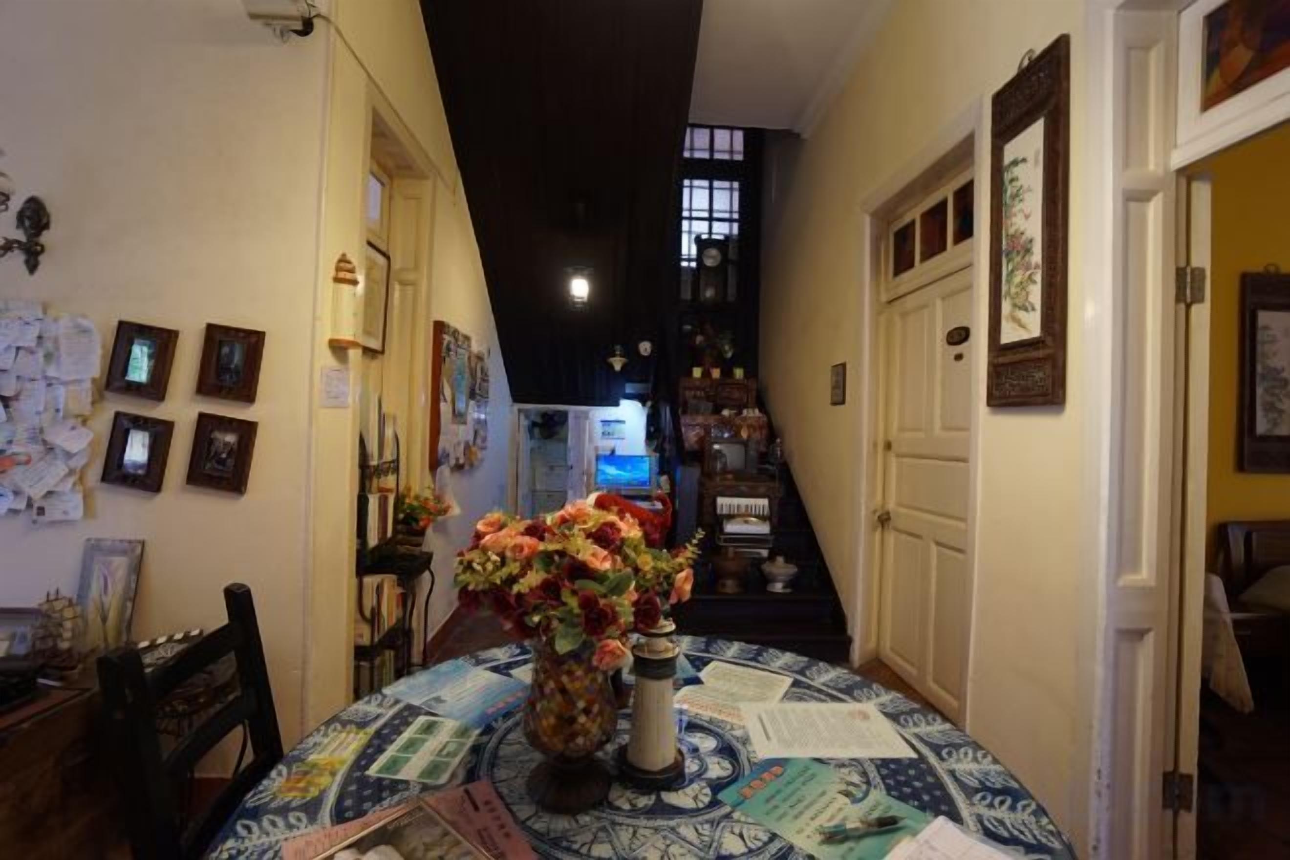 Un couloir étroit avec une table et des chaises de salle à manger, un escalier et une porte.