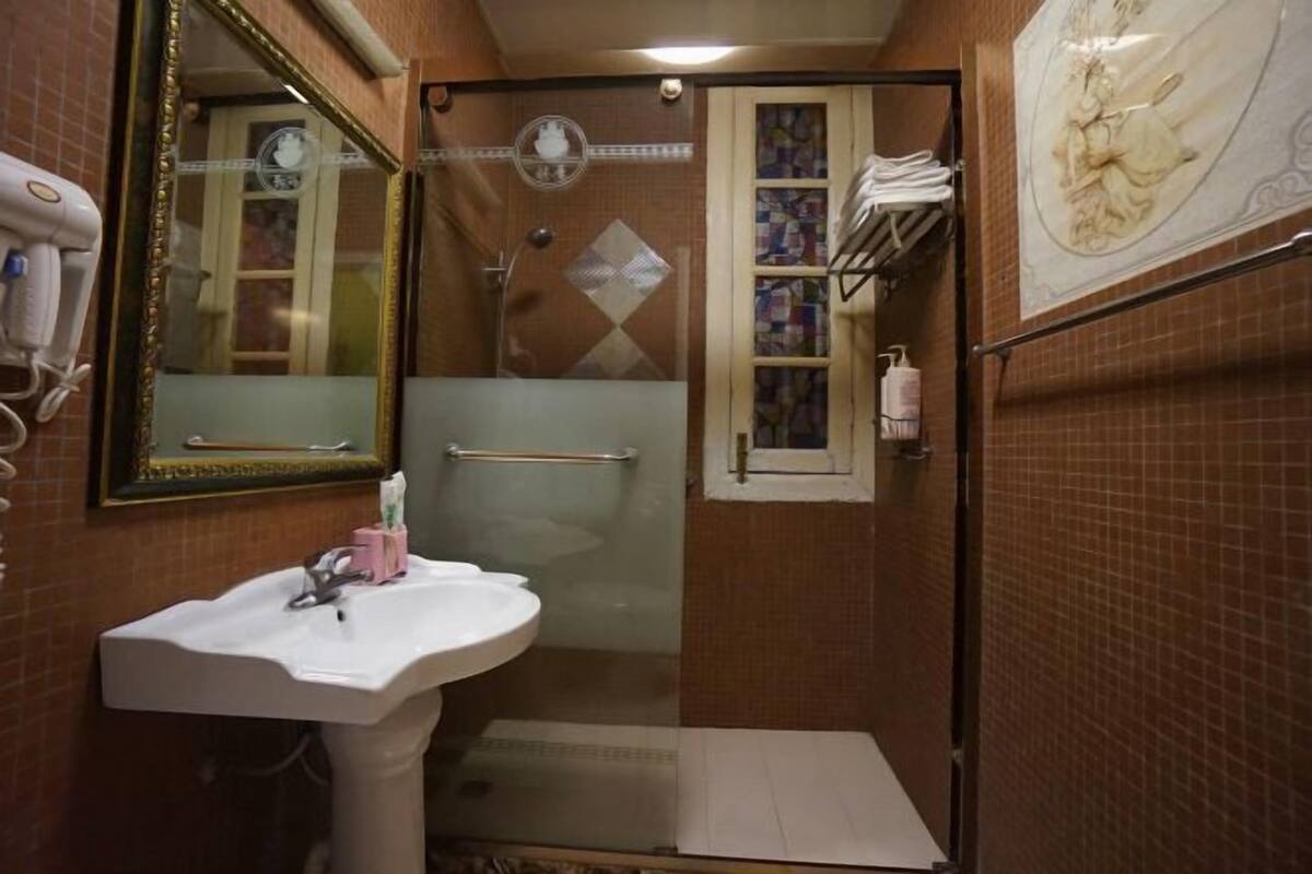 A bathroom with a white sink, a glass shower enclosure, and a mirror with a decorative frame.