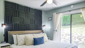 Un dormitorio con cama, mesita de noche, luz empotrada en la pared y vistas al exterior.