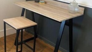 A small wooden desk with a stool, a glass container, and a small box on the floor. - Le Quai des Marins (Châteauroux)