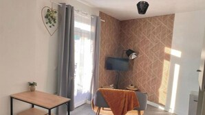 A modern living room with a dining area, a TV, and a patterned wall. - Le Quai des Marins (Châteauroux)