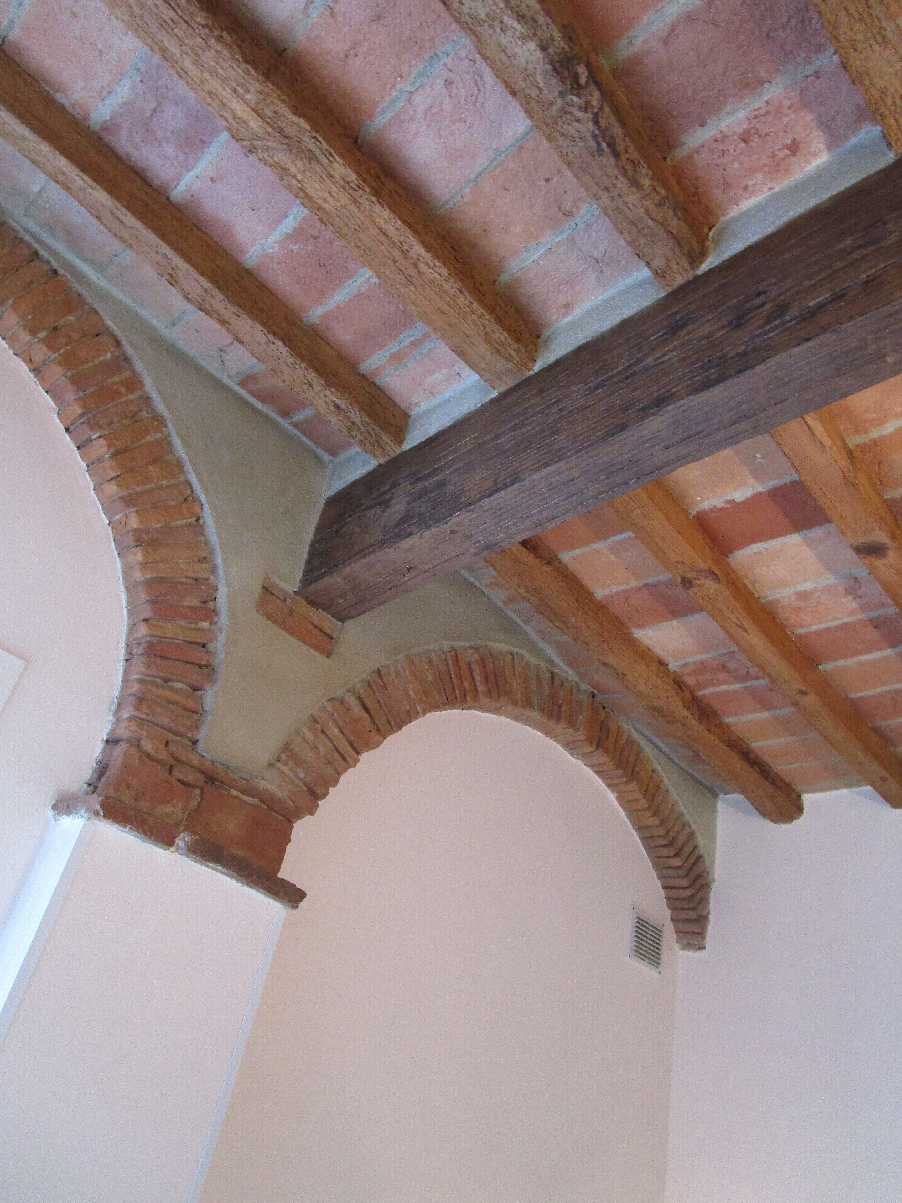 A room with exposed wooden beams and brick arches.