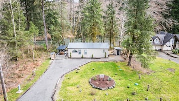 Surrounded by a lush forest, this property offers a peaceful retreat with a circular patio and a small shed.