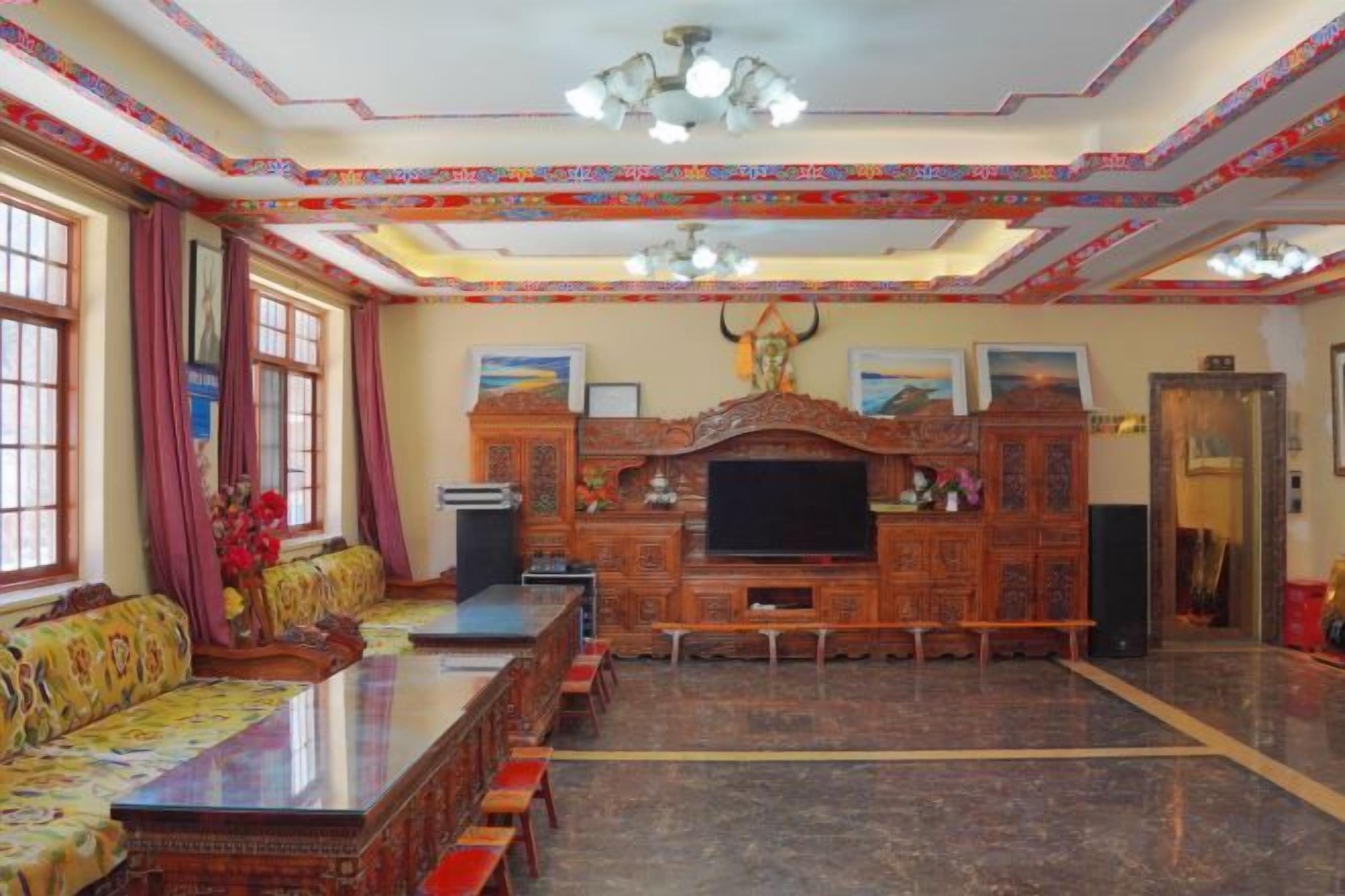 A spacious living room with a long wooden sofa, a television, and a fireplace.