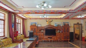 A spacious living room with a long wooden coffee table, a television, and a sofa set. - Dawagengzha Ecological Theme Hotel (Baoxing)