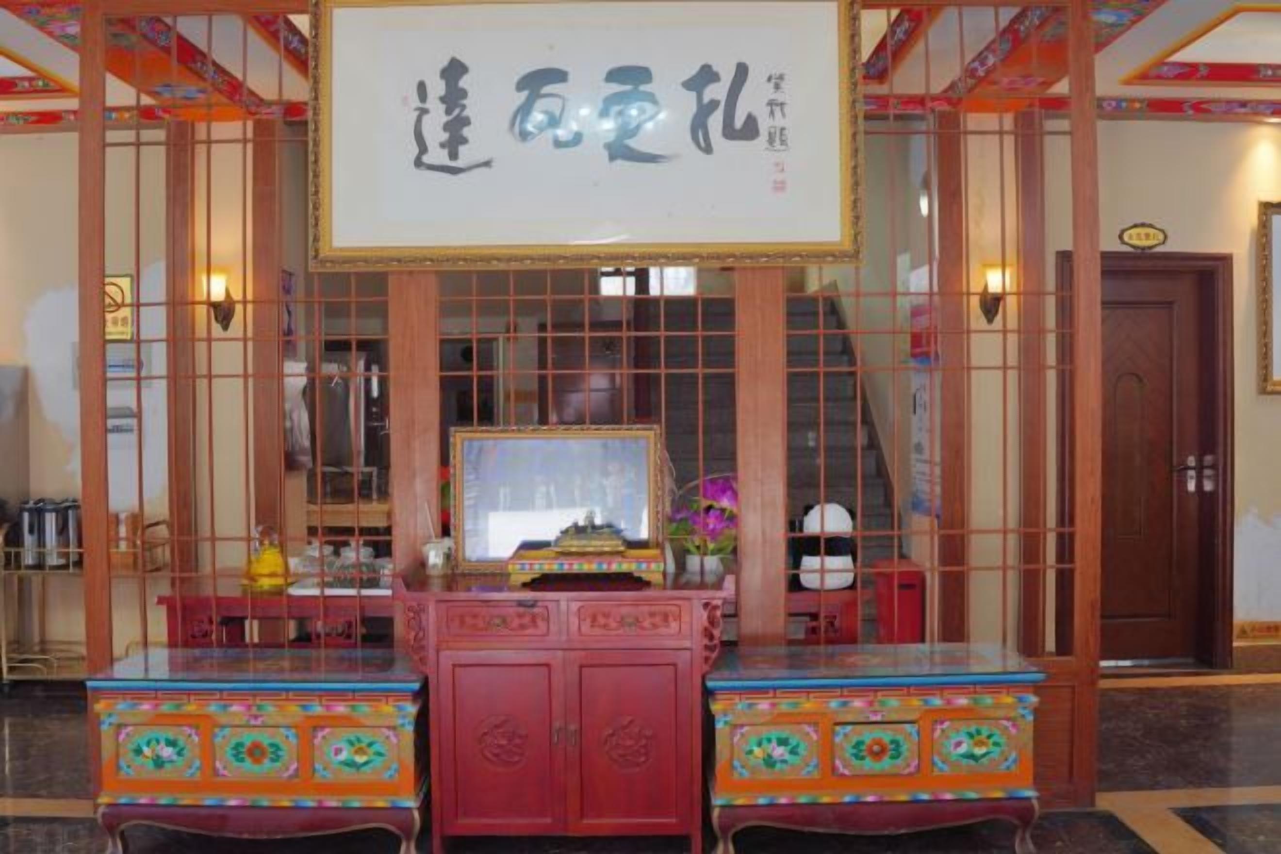 A traditional Chinese room with a large framed calligraphy piece, a wooden cabinet with intricate designs, and a door with a sign.