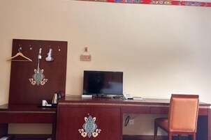 A wooden desk with a television, a chair, and a coat rack with hangers.