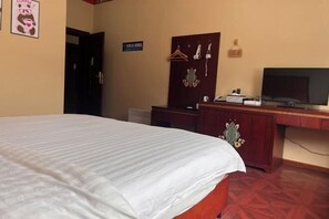 Ein Hotelzimmer mit einem Bett, einem Fernseher, einem Schreibtisch mit Computer und einem Kleiderschrank.