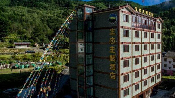 A multi-story building with a traditional architectural style, featuring a prominent sign with Chinese characters. - Dawagengzha Ecological Theme Hotel (Baoxing)