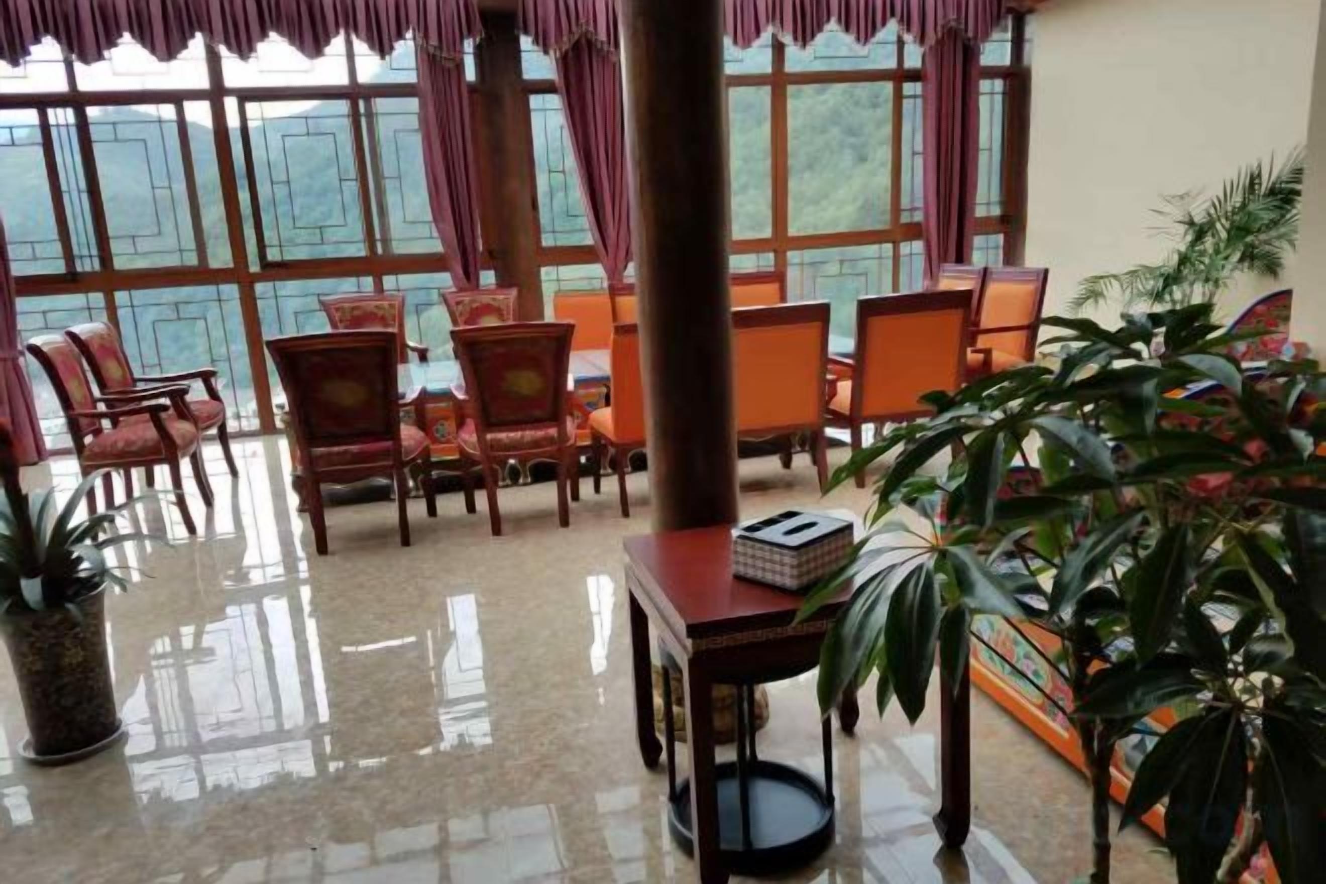 A room with a large window, several chairs, a table, and potted plants.