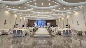 Un amplio salón con asientos escalonados, un escenario central y una gran pantalla al frente.