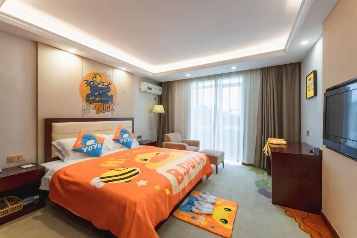 Une chambre d’hôtel avec un lit, un bureau, une chaise, une télévision et une fenêtre avec des rideaux.