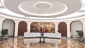 A hotel lobby with a reception desk, seating area, and a large mural on the wall.