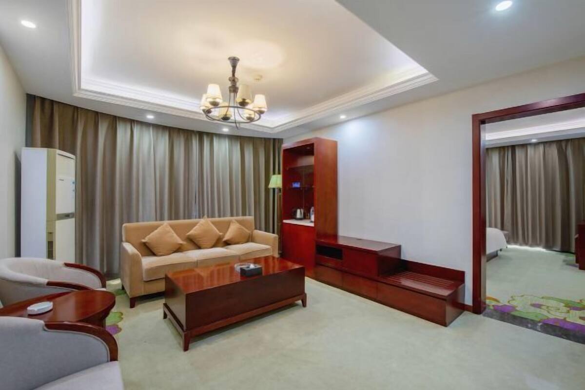 Une chambre d’hôtel équipée d’un canapé, d’une table basse, d’un meuble pour la télévision et d’un miroir.