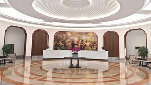 Un hall con una recepción central, un mural grande y un piso de mármol pulido.