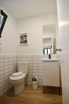 A small, clean bathroom with a toilet, sink, and mirror.