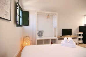 A bedroom with a bed, a TV, a fan, and a map on the wall.
