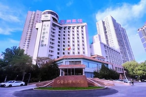 A multi-story hotel with a prominent entrance and a flag on top. - Bayin Guoleng Hotel (Korla)