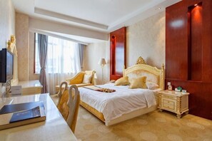 A hotel room with a large bed, a desk with a chair, a TV, and a nightstand with a lamp.