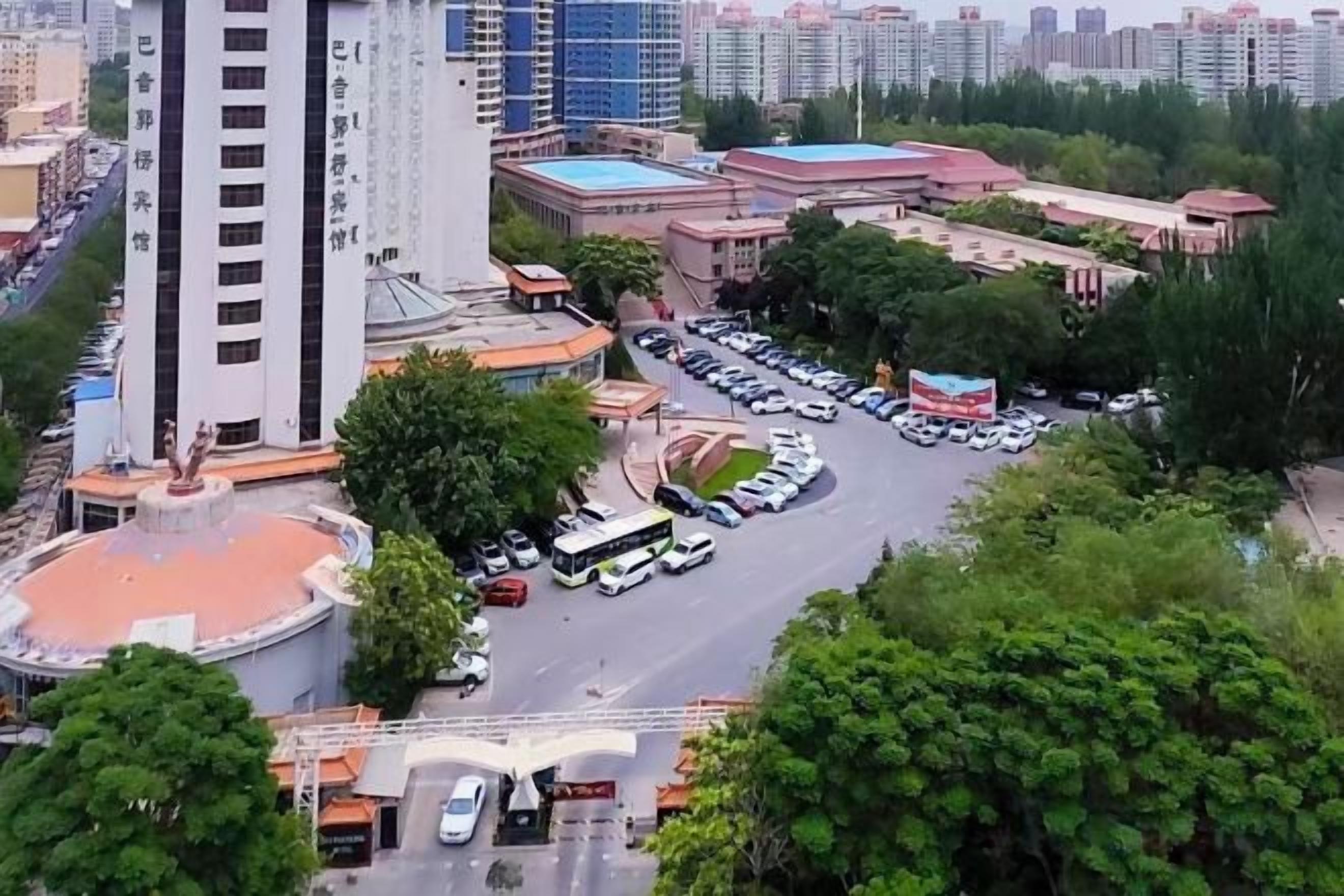 A multi-level parking structure with a central roundabout, surrounded by buildings and greenery.