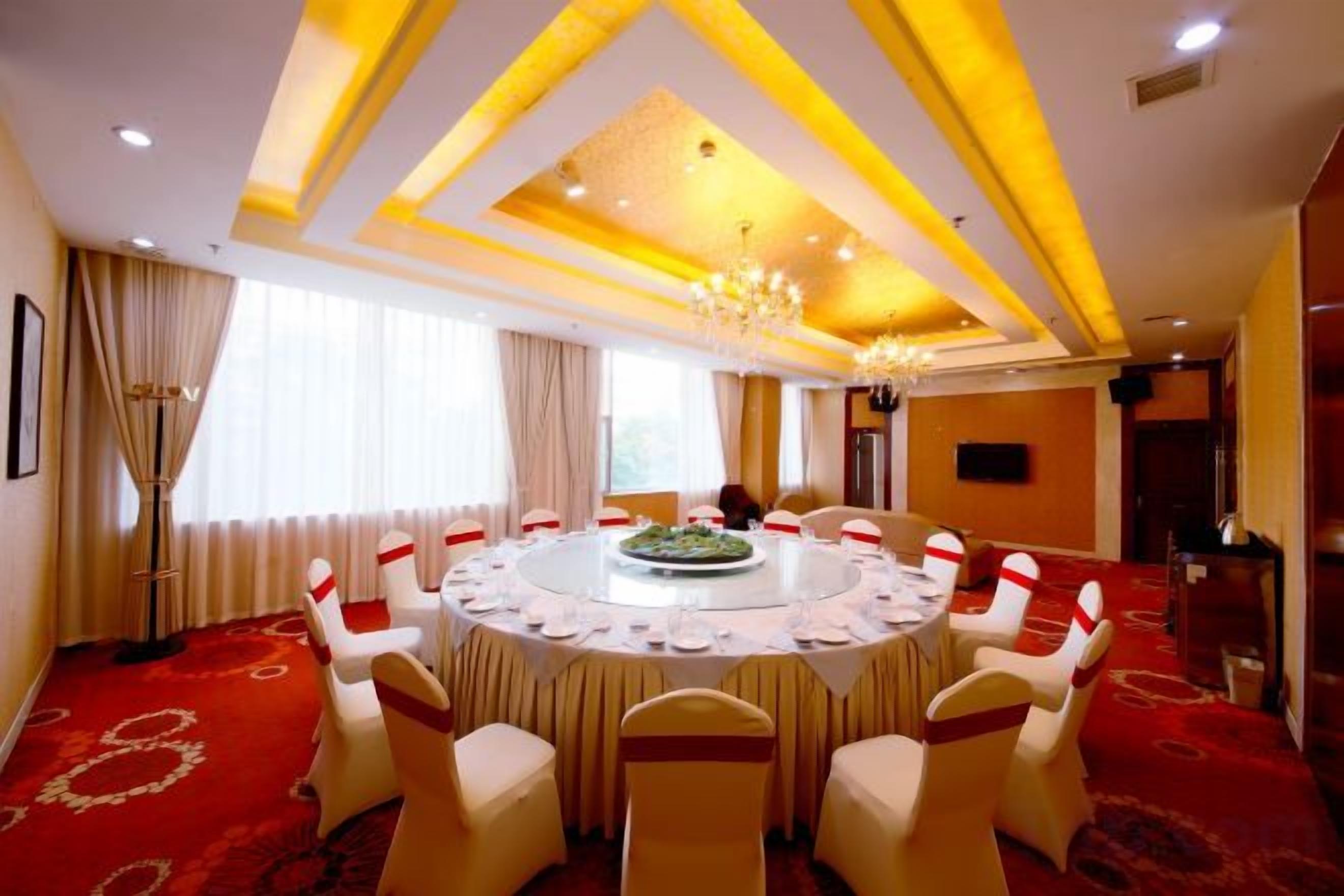 A conference room with a round table, chairs, and a chandelier.