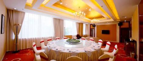 A conference room with a round table, chairs, and a chandelier.