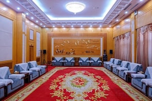 A conference room with a red carpet, rows of chairs, and a large wall mural. - Bayin Guoleng Hotel (Korla)