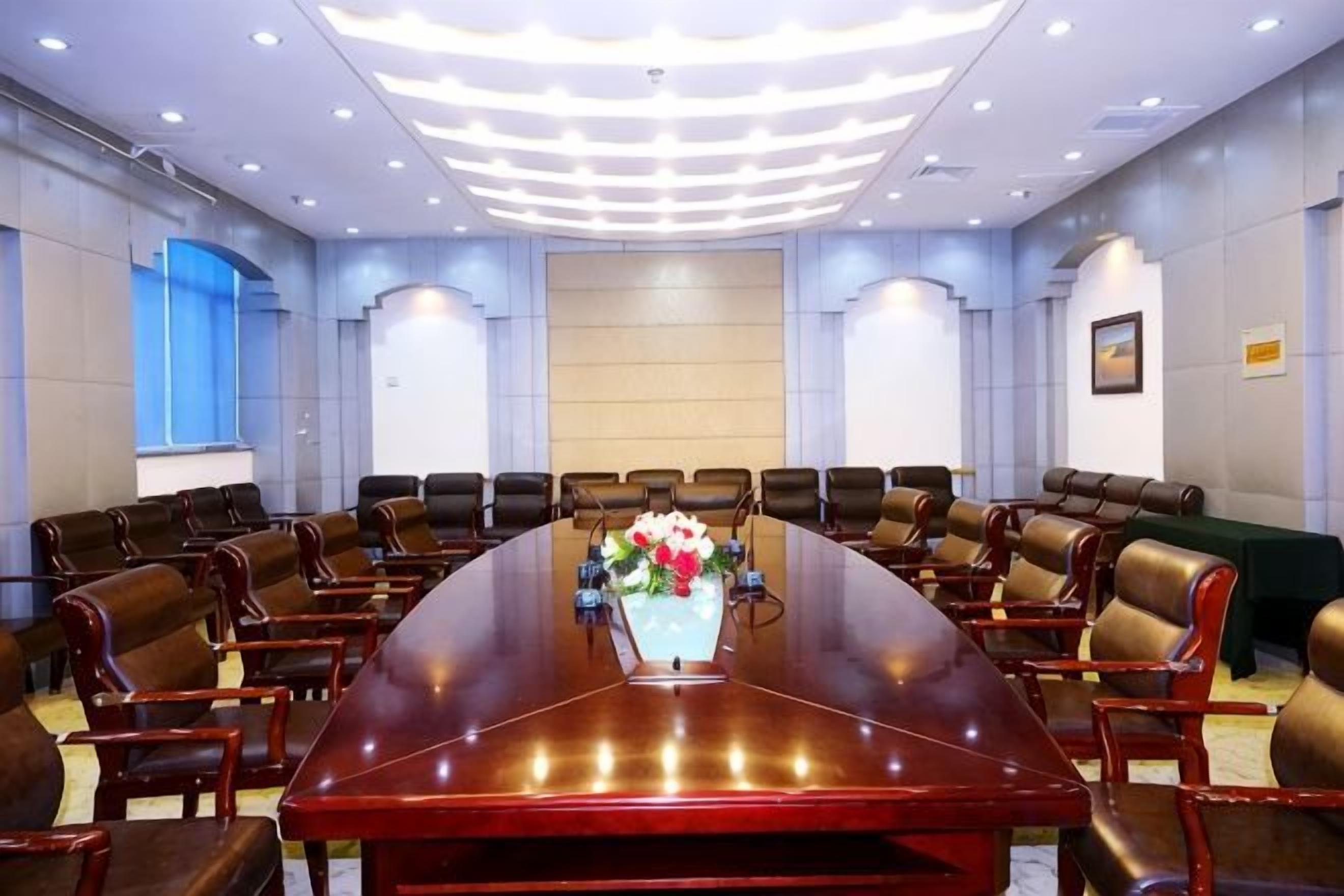 A conference room with a long table, multiple chairs, and a floral centerpiece.