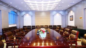 A conference room with a long table, multiple chairs, and a floral centerpiece.