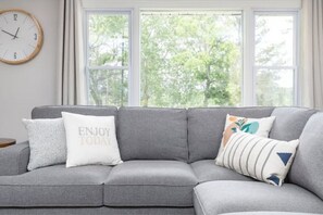Relax in this serene space with a comfortable sofa and a view of lush green trees.