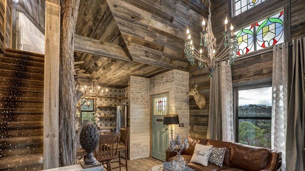 Un intérieur rustique avec un plafond en bois, un lustre, un canapé en cuir et un coin repas.