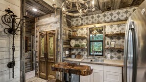 Une cuisine rustique avec des murs en bois, une table à manger en bois et un réfrigérateur en acier inoxydable.