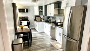 Una cocina moderna con electrodomésticos de acero inoxidable, muebles blancos y un suelo de madera en espiga.