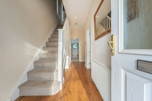 Staircase leads to an upper level, flanked by a door with a brass handle and a window.